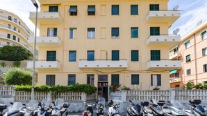 A multi-story building with balconies, a gated entrance, and parked scooters. - JOIVY Two Steps From The Sea In Genoa (Genoa)