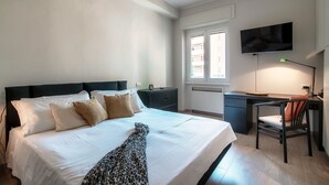 Une chambre à coucher avec un lit, un bureau, une chaise, une télévision et une fenêtre.