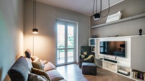 Un salon moderne avec un canapé, un téléviseur et une bibliothèque.