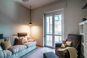 Un salon avec un canapé, un fauteuil et une suspension.