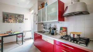 Une cuisine moderne avec des meubles de rangement rouges, une cuisinière à gaz et divers ustensiles de cuisine.