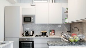 A modern kitchen with white cabinets, a built-in microwave, a gas stove, and a sink with a fruit bowl. - JOIVY Family Flat W/Balcony (Como)