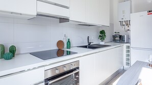 A modern kitchen with white cabinets, a stainless steel oven, a built-in microwave, and a water heater.
