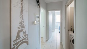 Ein Flur mit Wandkunstwerk von Eiffelturm, einer zur Toilette führenden Tür und einer sichtbaren Waschmaschine.