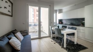 Eine moderne Wohnung mit Essbereich, einer Couch und einer Küche.