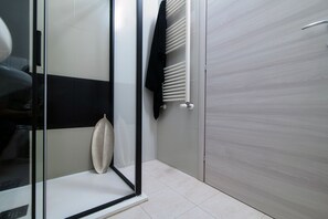 Une salle de bain moderne avec une douche à parois de verre, un porte-serviettes et un radiateur.