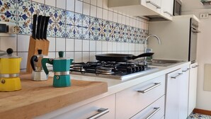 Et køkken med gasblus, kaffemaskine og elkedel på bordet.