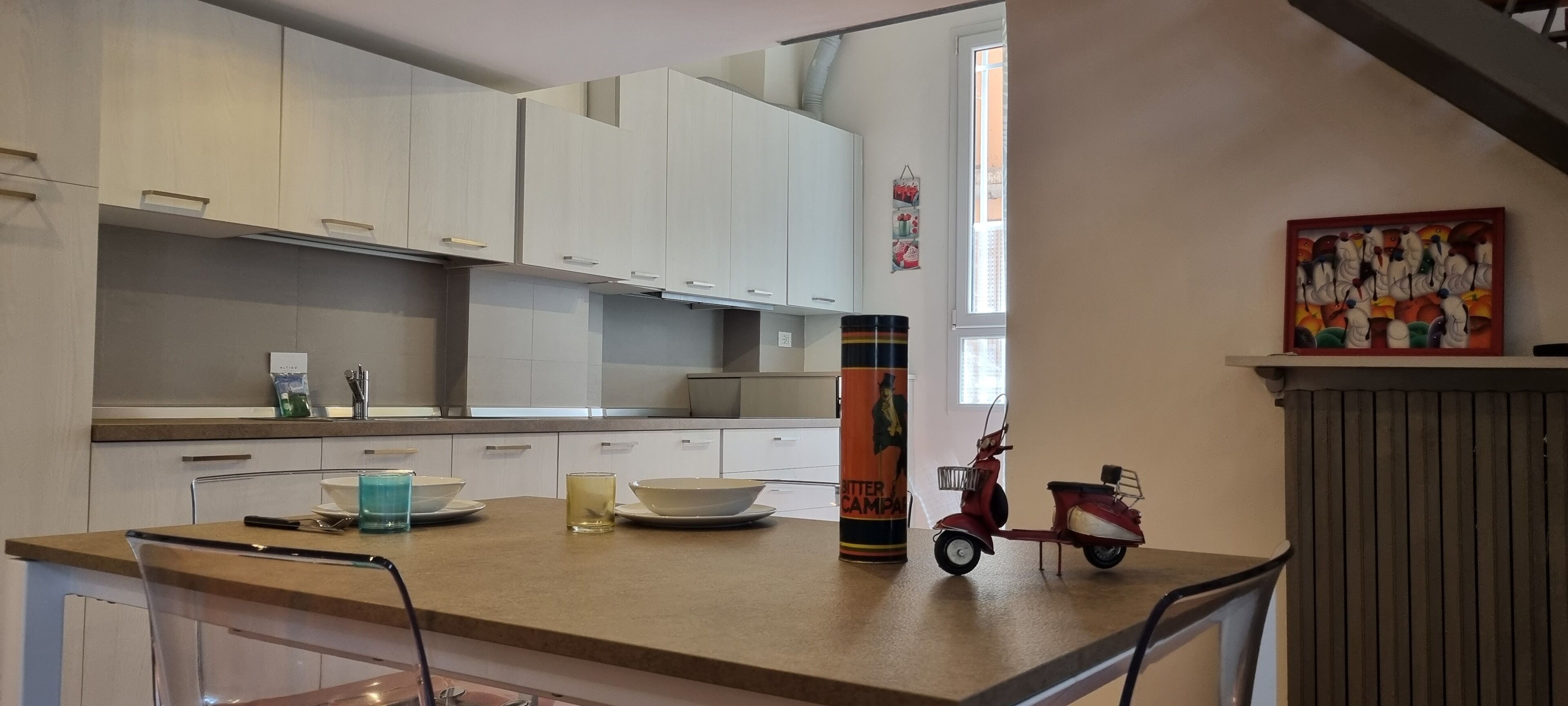 Une cuisine moderne avec des meubles blancs, un plan de travail et un coin repas.