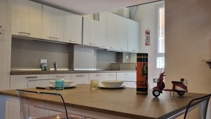 A modern kitchen with white cabinets, a countertop, and a dining area. - JOIVY Studio Near Porta Romana (Milan)