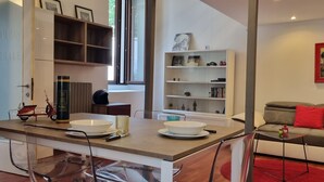 A modern living room with a dining area, a bookshelf, and a sofa. - JOIVY Studio Near Porta Romana (Milan)
