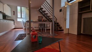 A spacious kitchen with modern appliances, a dining area with chairs, and a staircase leading to another level. - JOIVY Studio Near Porta Romana (Milan)
