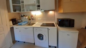 A compact kitchen with a washing machine, a microwave, and a sink.