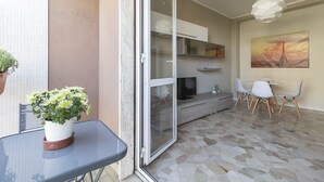 An interior space with a glass door leading to an outdoor area, a dining table with chairs, a flat-screen TV, and a painting on the wall. - JOIVY Trendy Flat W/Balcony (Milan)