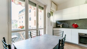 Una cocina moderna con armarios blancos, horno de acero inoxidable y comedor con mesa y sillas.