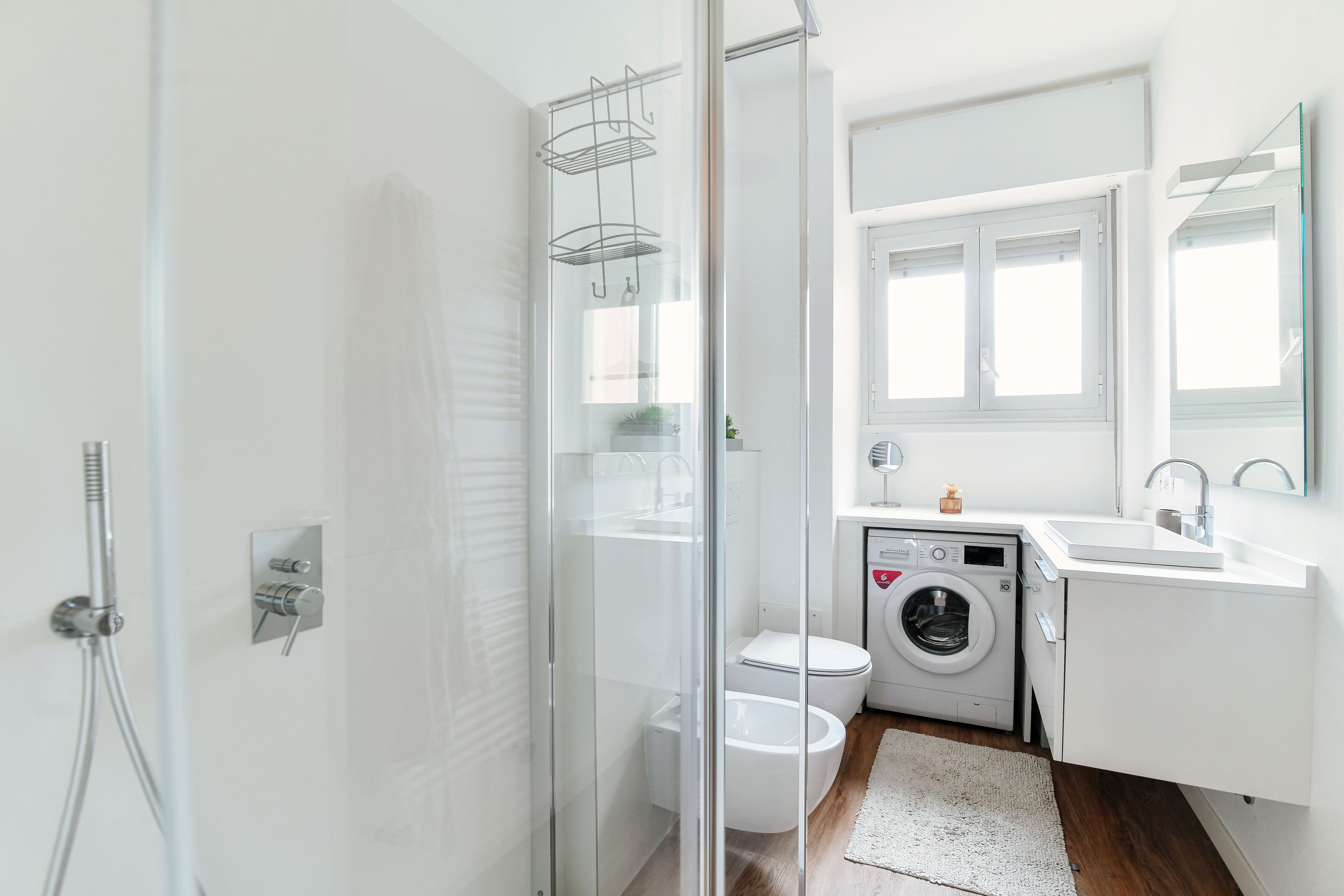 Une salle de bain moderne avec une douche à parois de verre, des toilettes, un lave-linge et un lavabo avec un miroir.