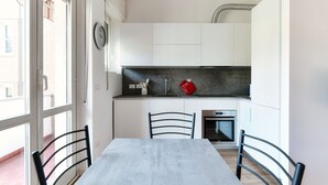 Una cocina moderna con gabinetes blancos, encimera negra y una mesa de comedor con sillas.