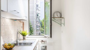 Une cuisine moderne avec une grande fenêtre, un évier, une plante et une horloge au mur.