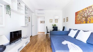 Un salon moderne avec un téléviseur, un canapé et un coin repas.