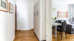 Un intérieur moderne avec un plancher en bois, une porte blanche, un coin repas avec une table et des chaises, et un canapé gris.
