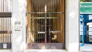 A building entrance with a metal gate, a fire alarm, and a sign with the word "DOMEN". - JOIVY Homey 1-Bed W/View Near Citylife (Milan)
