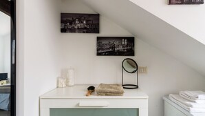 A bathroom with a white vanity, a mirror, and two black-and-white cityscape pictures on the wall. - JOIVY Classic Top-Floor Studio By Park (Milan)