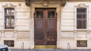 A building facade with a double wooden door, metal bars on windows, and a parking meter. - JOIVY Classic Top-Floor Studio By Park (Milan)
