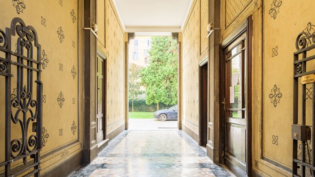 A hallway with patterned walls and a tiled floor leading to a door. - JOIVY Classic Top-Floor Studio By Park (Milan)