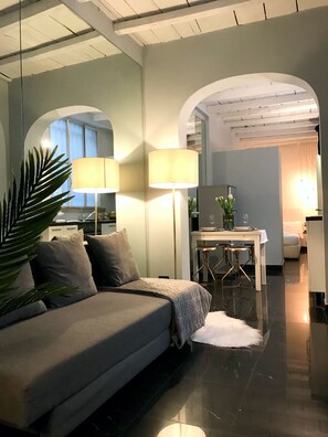 A modern living room with a sofa, lamps, and a dining area with a table and chairs. - JOIVY Bright Flat In The Centre (Milan)