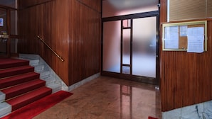 A hotel lobby with a marble staircase, wooden paneling, and a bulletin board with papers. - JOIVY Cosy 1Bed Flat In Fiera (Milan)