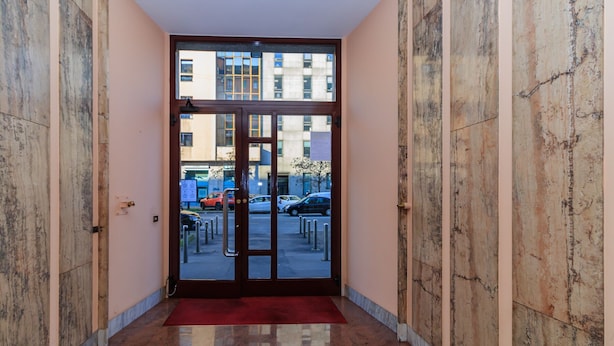 A hallway with a glass door leading to a parking area. - JOIVY Cosy 1Bed Flat In Fiera (Milan)