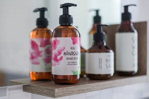 A row of hand soap bottles on a wooden shelf.