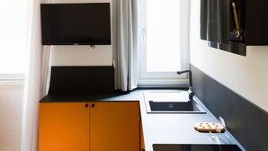 Et moderne køkken med en sort bordplade, vask og et vindue med gardiner.