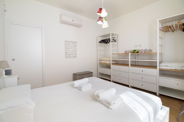 Une chambre à coucher comprenant un lit, une armoire, une table de chevet et un climatiseur fixé au mur.