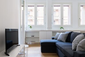 A modern living room with a flat-screen TV, a dark blue sofa, and a white console table.