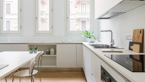 A modern kitchen with white cabinets, a wooden countertop, and a window overlooking a residential area. - JOIVY Lovely 1-Bed W/Balcony & Parking (Milan)