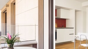 A modern kitchen with white cabinets, a red backsplash, and a wooden floor. - JOIVY Stylish 1-Bedroom Flat (Milan)