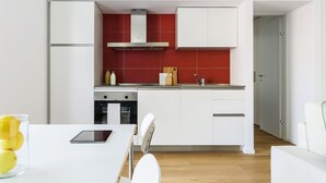A modern kitchen with white cabinets, a red backsplash, and a stainless steel range hood. - JOIVY Stylish 1-Bedroom Flat (Milan)