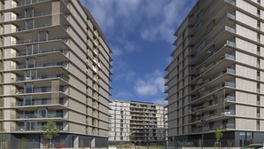 Un immeuble résidentiel moderne à plusieurs étages, doté de balcons, d’une cour intérieure et offrant une vue sur un ciel dégagé.