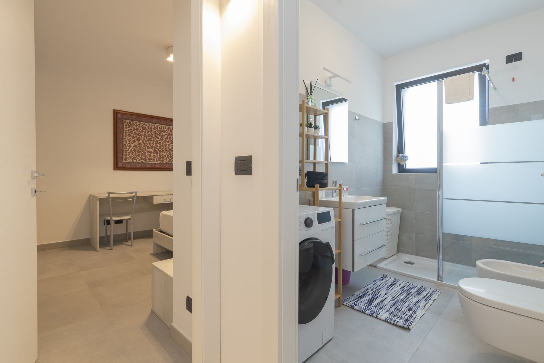 A modern bathroom with a shower, toilet, and washing machine.