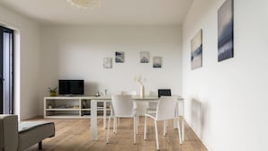 A modern living room with a dining area, white furniture, and artwork on the walls.