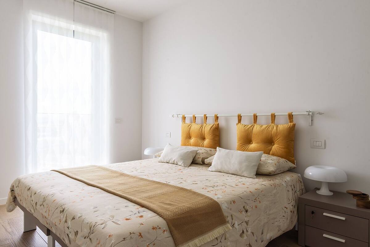A bedroom with a bed, bedside tables, and a window with curtains.