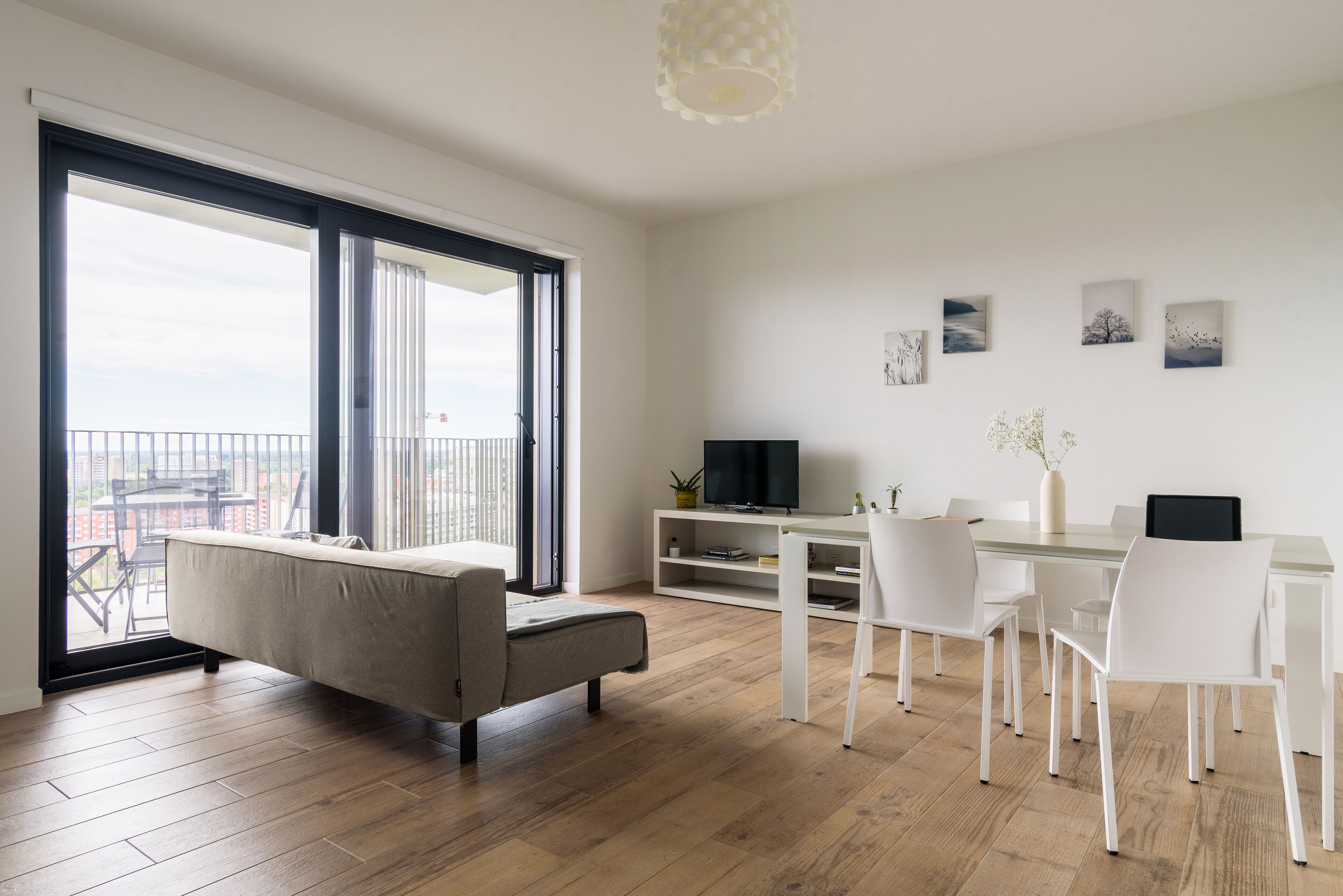 A modern living room with a sofa, TV, dining table, and chairs.