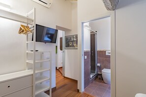 Casa de banho moderna com chuveiro, sanita e televisão montada.