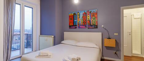 Habitación de hotel con una cama grande, un radiador, una ventana con cortinas y un cuadro en la pared.