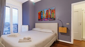 Une chambre avec un grand lit, un radiateur, une œuvre d’art accrochée au mur et une porte.