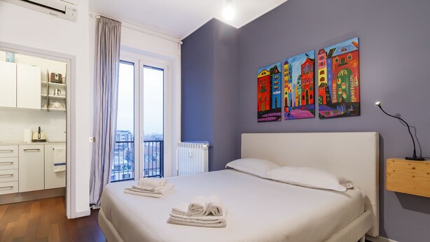 Une chambre à coucher avec un lit, une fenêtre avec des rideaux, un radiateur et un tableau accroché au mur.