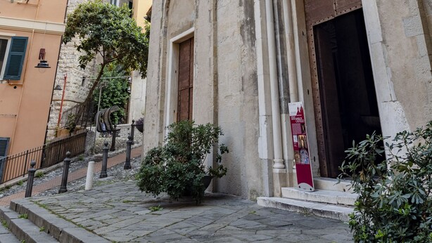 A historic building with a large arched entrance, stone columns, and a tower with battlements. - JOIVY Flat In Perfect Centre (Genoa)