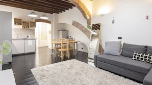 A modern living room with a grey sofa, white fluffy rug, and wooden dining table with chairs. - JOIVY Flat In Perfect Centre (Genoa)