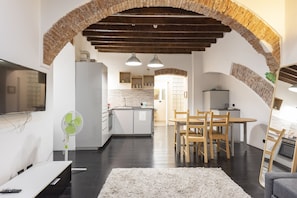 Um espaço moderno com cozinha, área de refeições e televisão.
