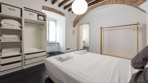 A bedroom with a bed, a wardrobe, a hanging rack, and a brick archway. - JOIVY Flat In Perfect Centre (Genoa)